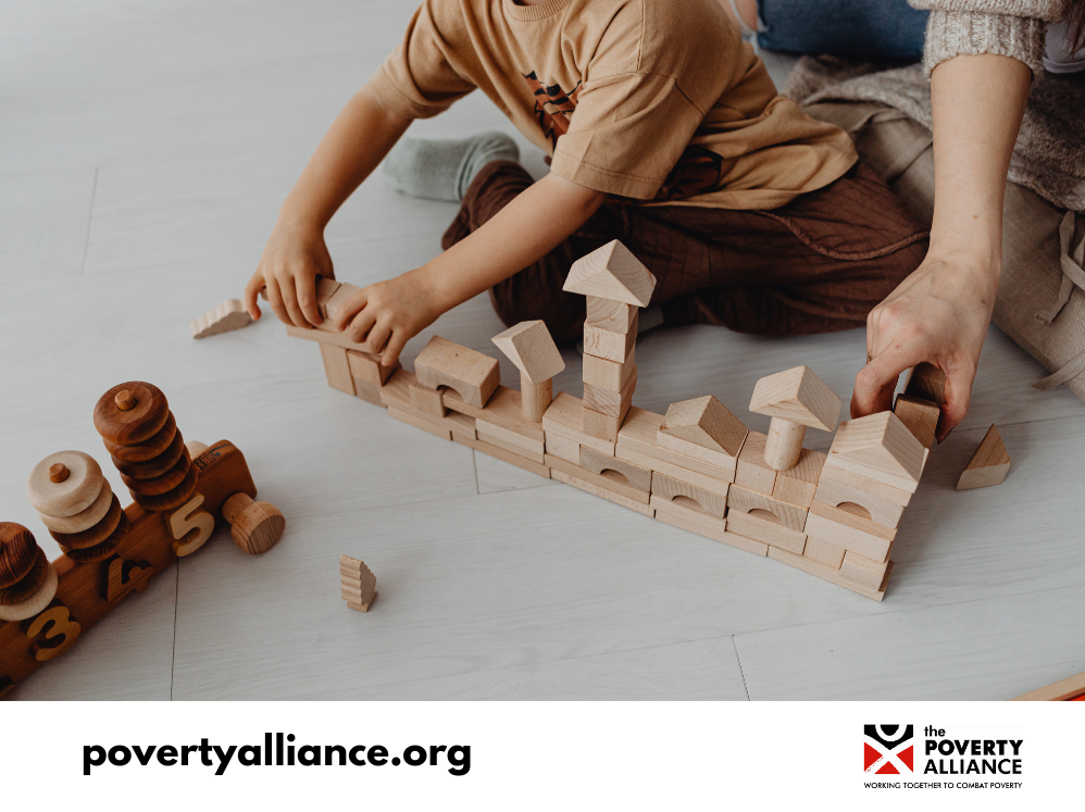 A stock image featuring the hands of a young boy and his father, building a town out of wooden blocks.